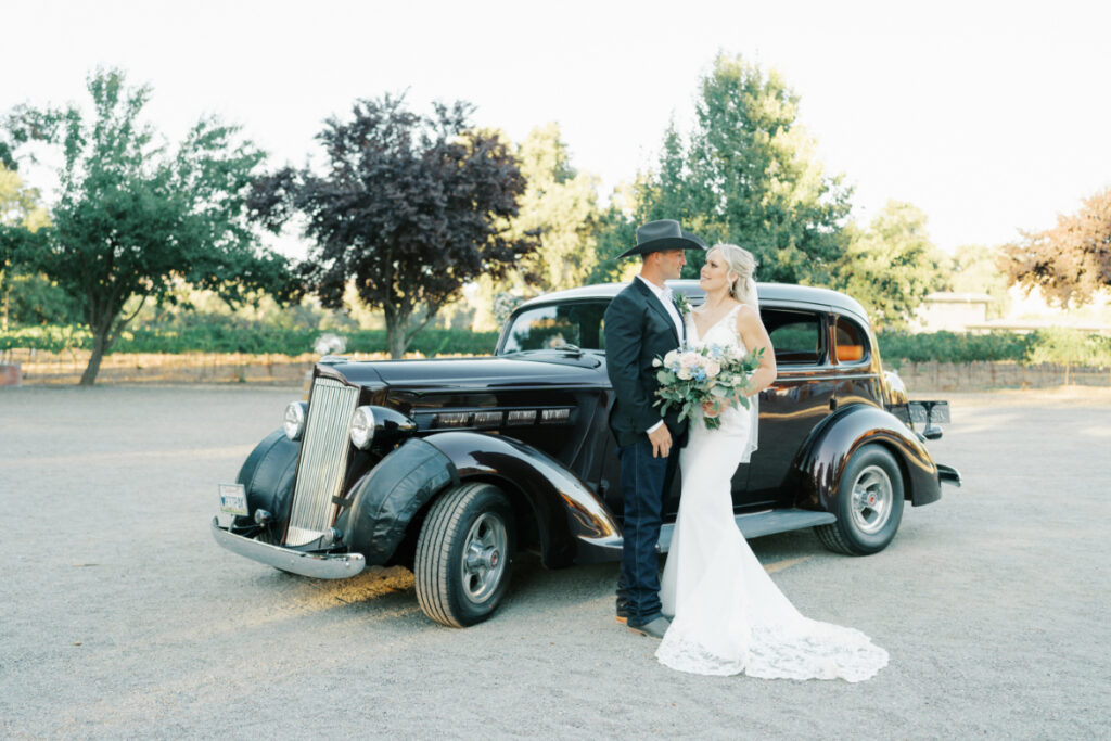 San Francisco bride and groom pose in front of a classic car as they look in each other's eyes. Bride wears San Francisco bridal shop find