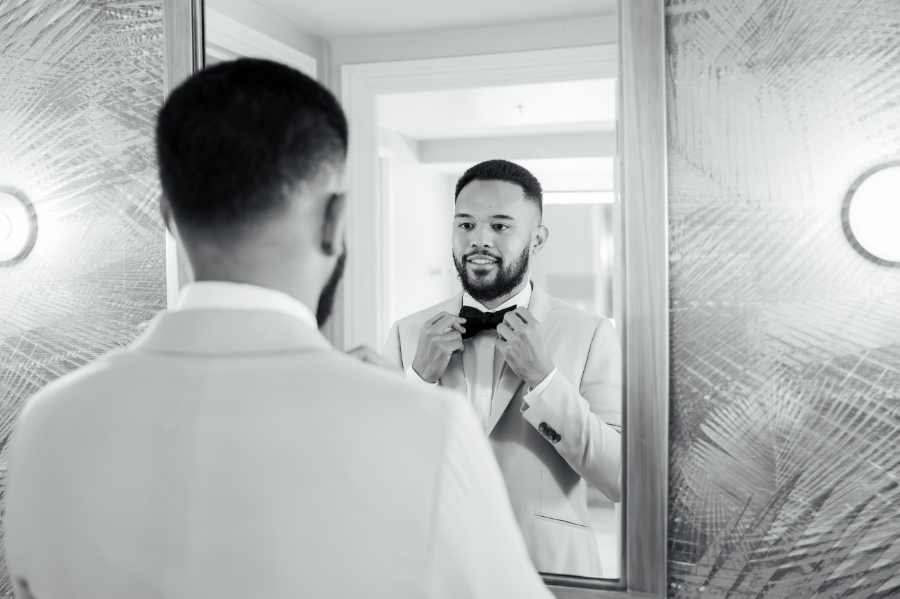 Groom adjusts bow tie in the mirror before his San Jose wedding day