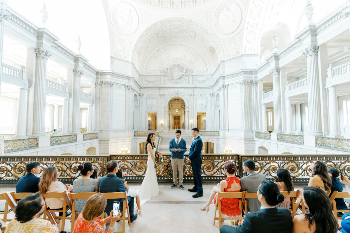 Bride and groom stand with officiant at their San Francisco city hall wedding