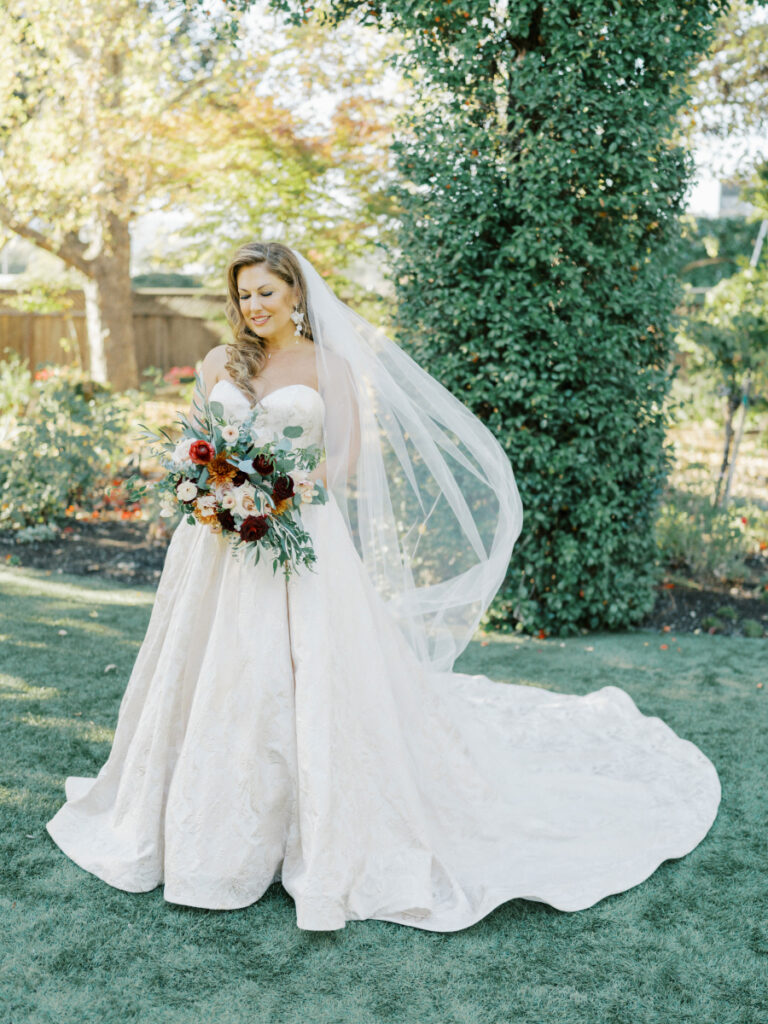 Bride holds red and White flowers as her veil blows in the wind