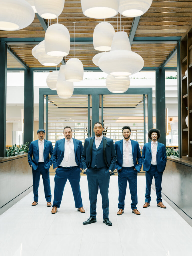 groom stands in the middle just ahead of the groomsmen as they pose for the camera