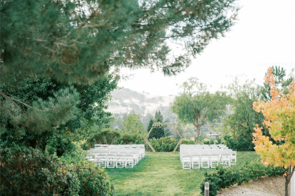 Empty white chairs in rows with a wedding arch. Picture of the ceremony spot before guests arrive to wedding at San Francisco wedding venues